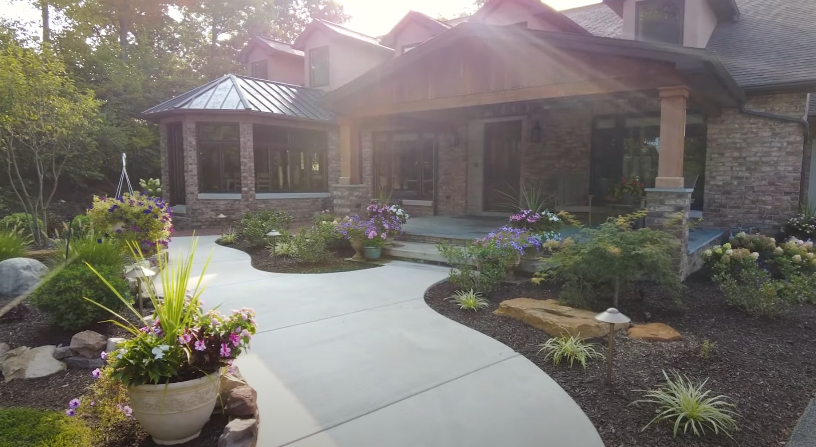 Custom front yard landscape design with hardscaping and colorful plantings Professional front yard landscaping with curved walkway, colorful flower beds, and stone accents around modern home